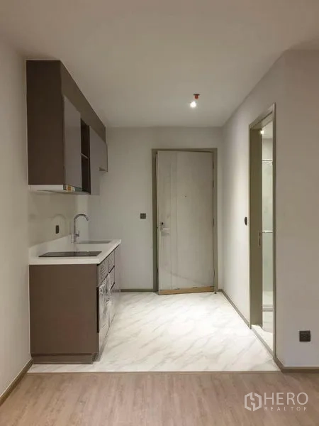 Condominium for sale in Watthana, Bangkok - Built-in kitchenette with sink, upper cabinets and entry hall in neutral tones.