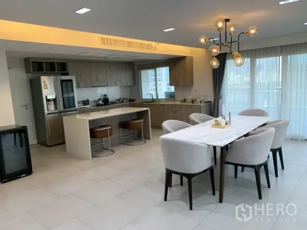 Condominium for rent in Sathon, Bangkok - Open-plan dining and modern kitchen with island, light tile floors and pendant lighting in a Sathon condo.