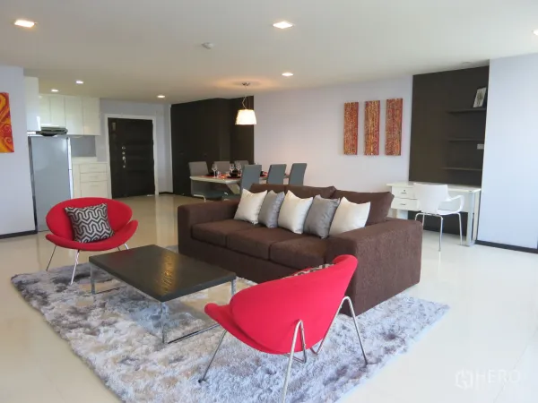 คอนโด ให้เช่าหรือขายในWatthana, Bangkok - ห้องนั่งเล่นกว้าง โซฟาสีน้ำตาล เก้าอี้สีแดง และพรมขนนุ่ม