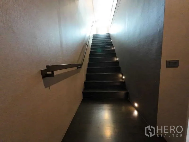 联排别墅 出租或出售在Lat Phrao, Bangkok - 狭长楼梯，墙面扶手与踏步灯通往楼上。