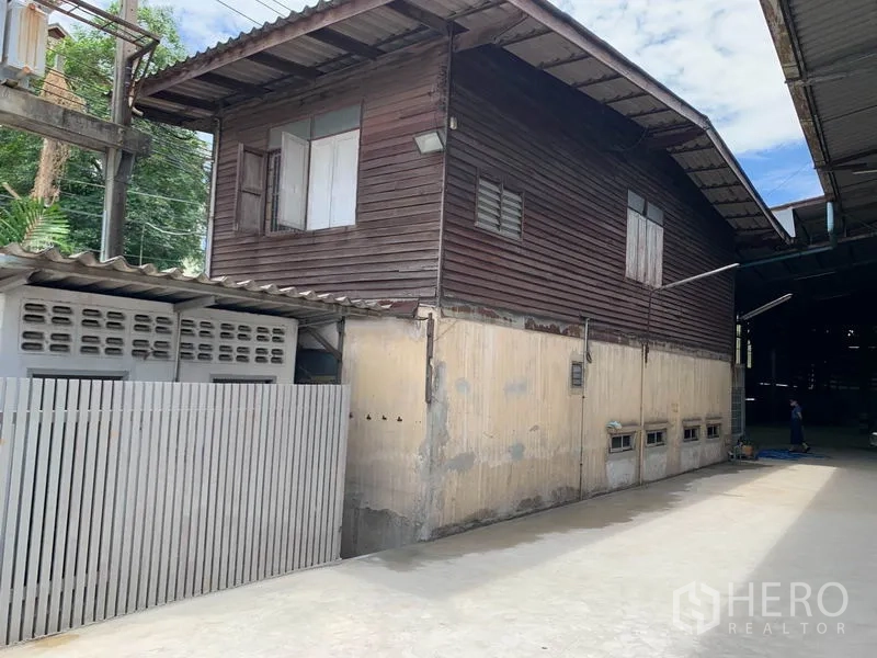 Warehouse for rent in Yan Nawa, Bangkok - Attached office building with wooden upper level beside the warehouse and a gated lane.