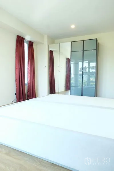 Home Office for rent in Wang Thonglang, Bangkok - Bedroom with large windows, mirrored wardrobe and wood flooring.