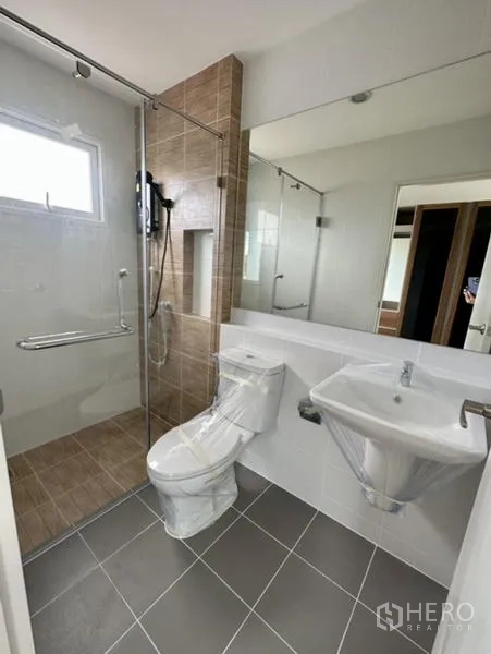 Townhouse for rent in Bang Phli, Samut Prakan - Clean bathroom with glass shower, brown tile and wide mirror.