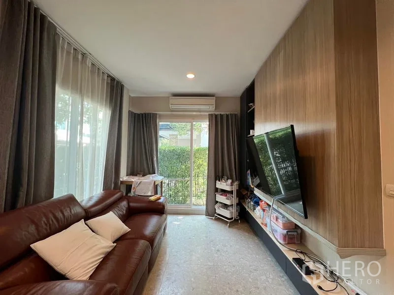 บ้าน ให้เช่าหรือขายในSaphan Sung, Bangkok - ห้องนั่งเล่นอบอุ่น โซฟาหนังสีน้ำตาล ผนังทีวี ประตูกระจกบานเลื่อน