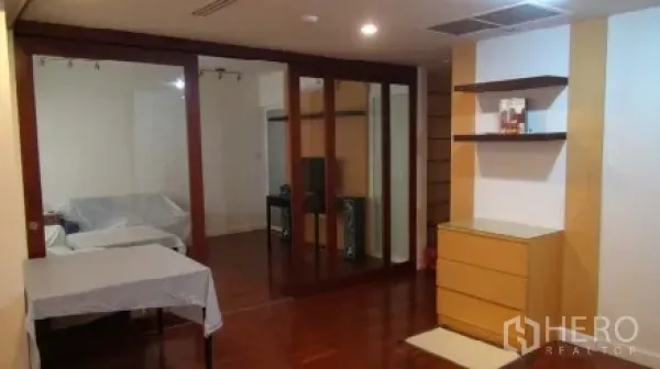 Condominium for rent or sale in Sathon, Bangkok - Open-plan living area with polished wood floors, sliding glass partitions, and built-in shelving in a Sathon condo.