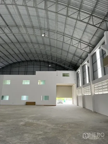 Factory for rent or sale in Bang Bo, Samut Prakan - Spacious production hall with high arched steel roof, white office block and large roller door.