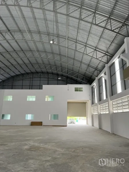 Factory for rent or sale in Bang Bo, Samut Prakan - Spacious production hall with high arched steel roof, white office block and large roller door.