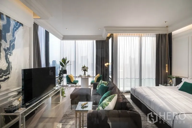 公寓 出租在Bang Rak, Bangkok - 起居与睡眠一体空间，电视柜、转角沙发与大面积玻璃。