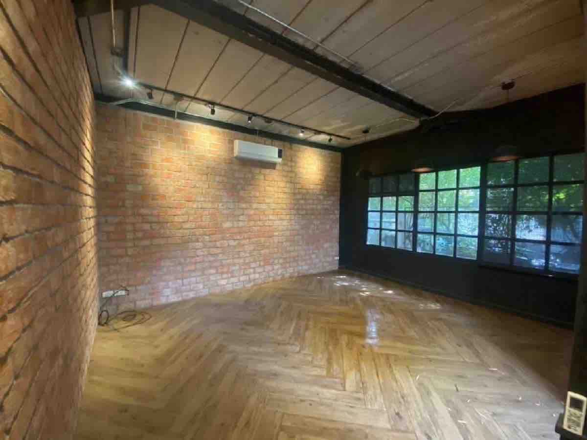 零售空间 出租在Watthana, Bangkok - Loft风格零售室：外露红砖、鱼骨纹木地板、轨道灯与黑色金属窗框。