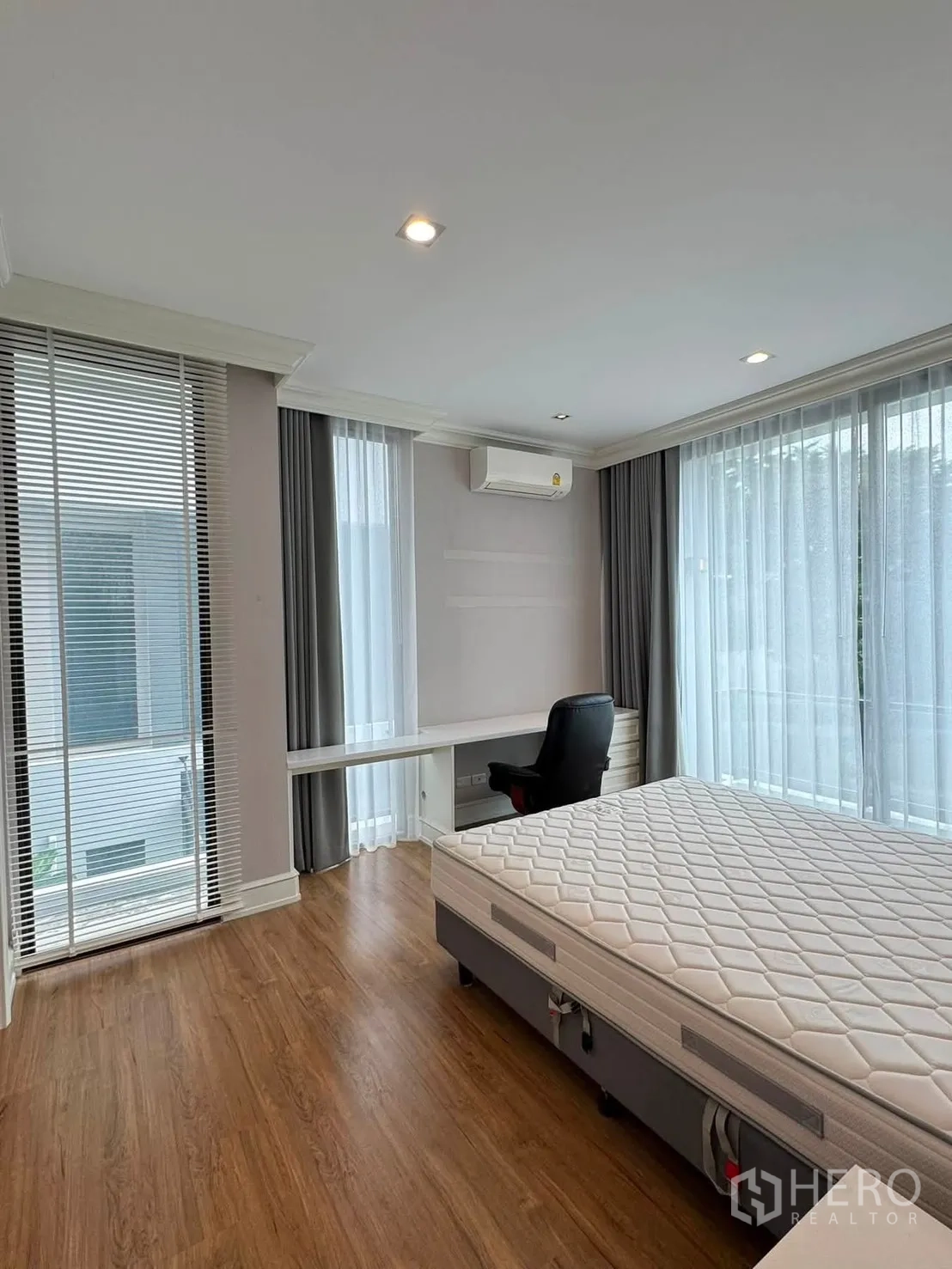 Townhouse for rent in Lat Phrao, Bangkok - Bright bedroom with large windows, desk and mattress.