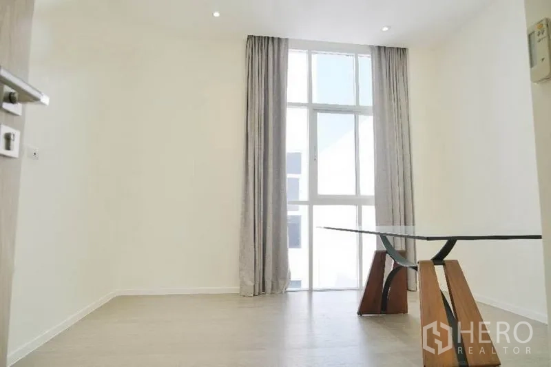 Home Office for rent or sale in Prawet, Bangkok - Bright office room with tall window and a glass-top desk.