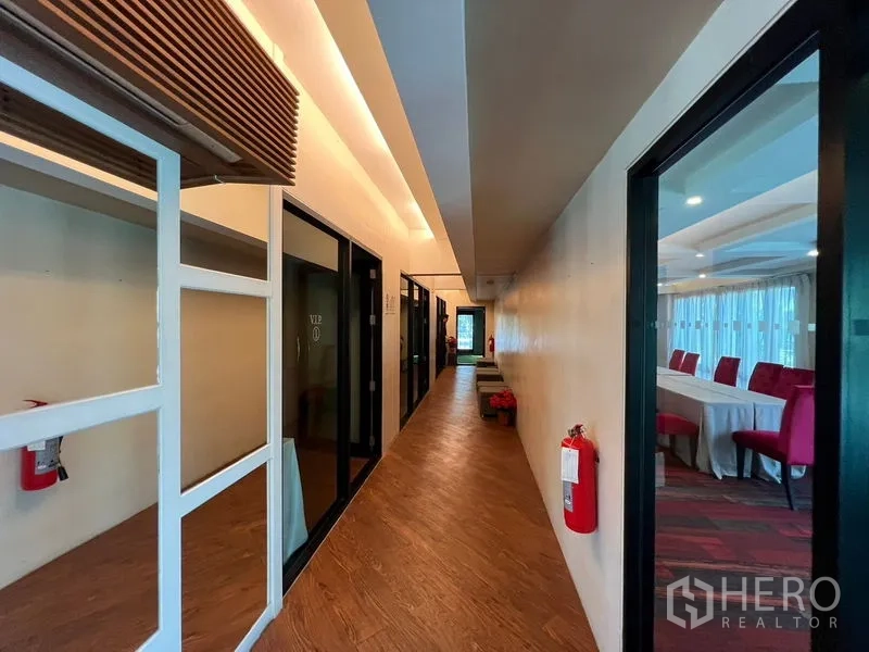 店屋 出租在Suan Luang, Bangkok - 走廊两侧为玻璃房间，旁有摆放红椅的会议空间。