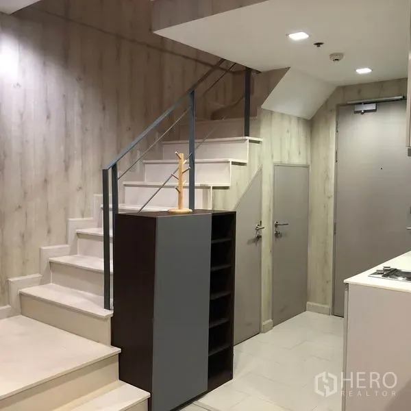 Condominium for rent or sale in Phra Khanong, Bangkok - Entrance hall featuring built-in storage, a modern staircase and a compact kitchen area.