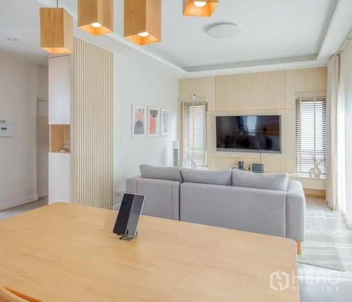 Detached House for rent in Bang Khun Thian, Bangkok - Living room toward TV feature wall with large sofa and light wood accents.