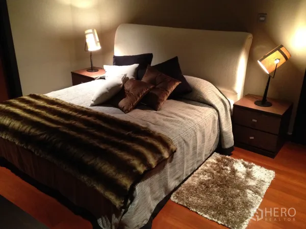 Condominium for rent in Bang Rak, Bangkok - Cozy bedroom with upholstered headboard, bedside tables and ambient lamps, layered with soft textiles.