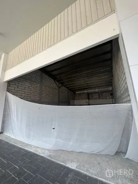 零售空间 出租在Khlong Toei, Bangkok - 宽门面商铺毛坯，前方挂有布帘，高挑金属屋顶，临近 Ekkamai。