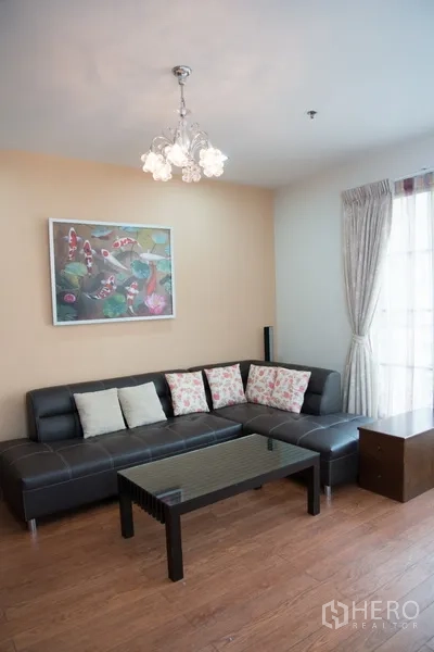 คอนโด ให้เช่าในKhlong Toei, Bangkok - มุมพักผ่อนอบอุ่น โซฟาหนังสีดำ โต๊ะกลางกระจก และโคมไฟ บนพื้นไม้