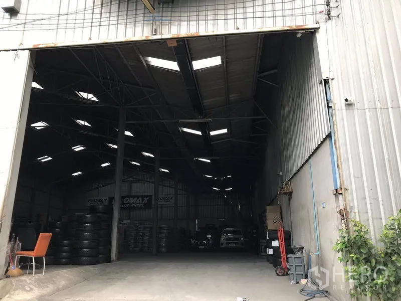 Warehouse for rent in Samut Prakan - Wide, high-clearance warehouse entrance with roof skylights and storage area inside.