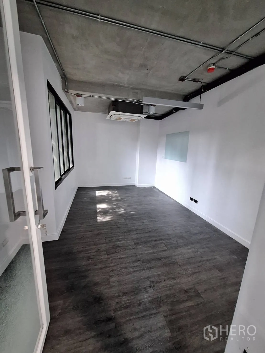 Office Space for rent - Small private office or meeting room with glass door, window and exposed ceiling.