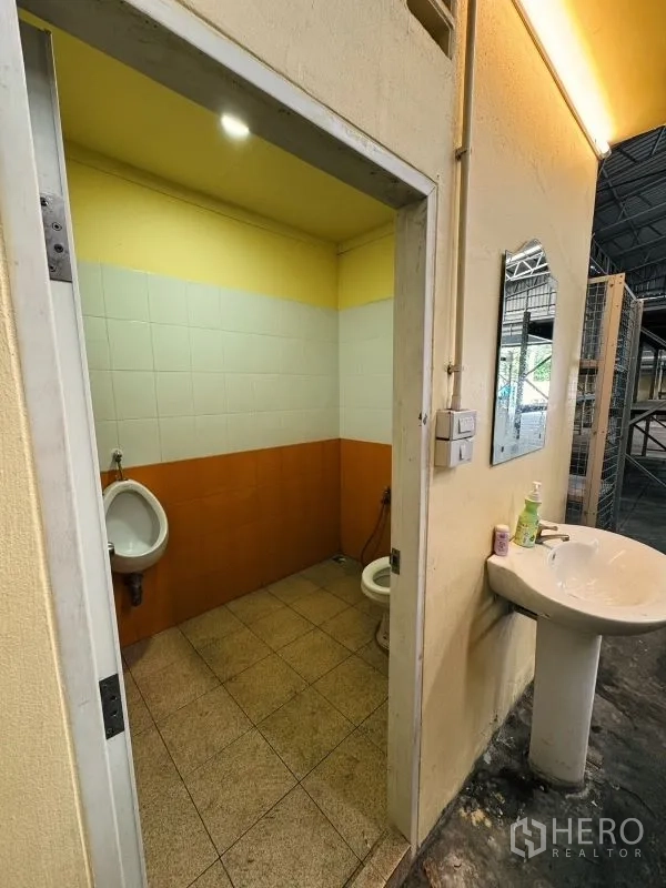 Warehouse for rent in Din Daeng, Bangkok - Warehouse restroom with toilet, urinal and sink beside the main storage area.