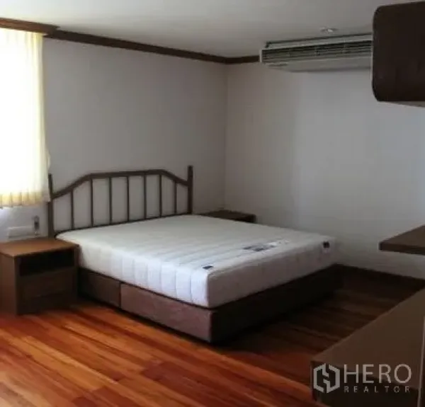 Condominium for rent in Watthana, Bangkok - Primary bedroom with wood flooring, double bed, bedside tables and wall-mounted air conditioner.