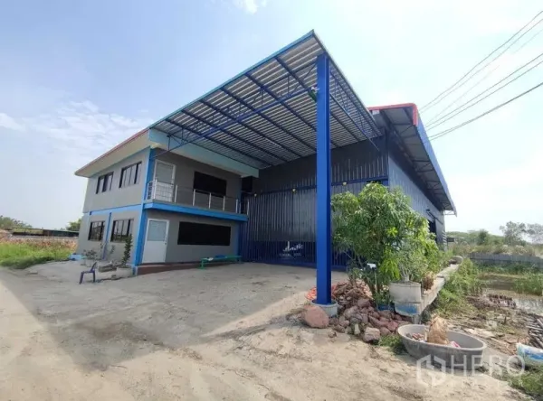 Warehouse for sale in Nakhon Pathom - Two‑storey office attached to a steel warehouse with a covered loading bay and wide concrete yard in Bang Yai, Nonthaburi.