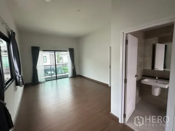 Detached House for sale in Khlong Sam Wa, Bangkok - Master bedroom with sliding doors to a balcony and an ensuite bathroom entrance