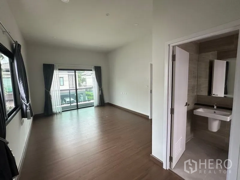 Detached House for sale in Khlong Sam Wa, Bangkok - Master bedroom with sliding doors to a balcony and an ensuite bathroom entrance