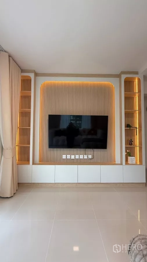 บ้าน ให้เช่าในBang Phli, Samut Prakan - ผนังทีวีบิวท์อินในห้องนั่งเล่นพร้อมชั้นวางและทีวีขนาด 65 นิ้ว.