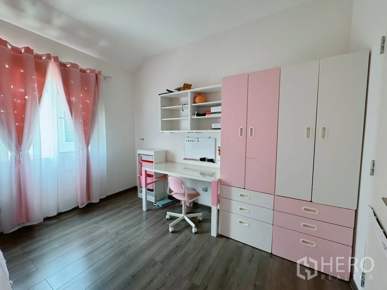 Detached House for rent or sale in Bang Phli, Samut Prakan - Bright kids’ or study room with pink curtains, white and pink wardrobe, and desk on wood floors.