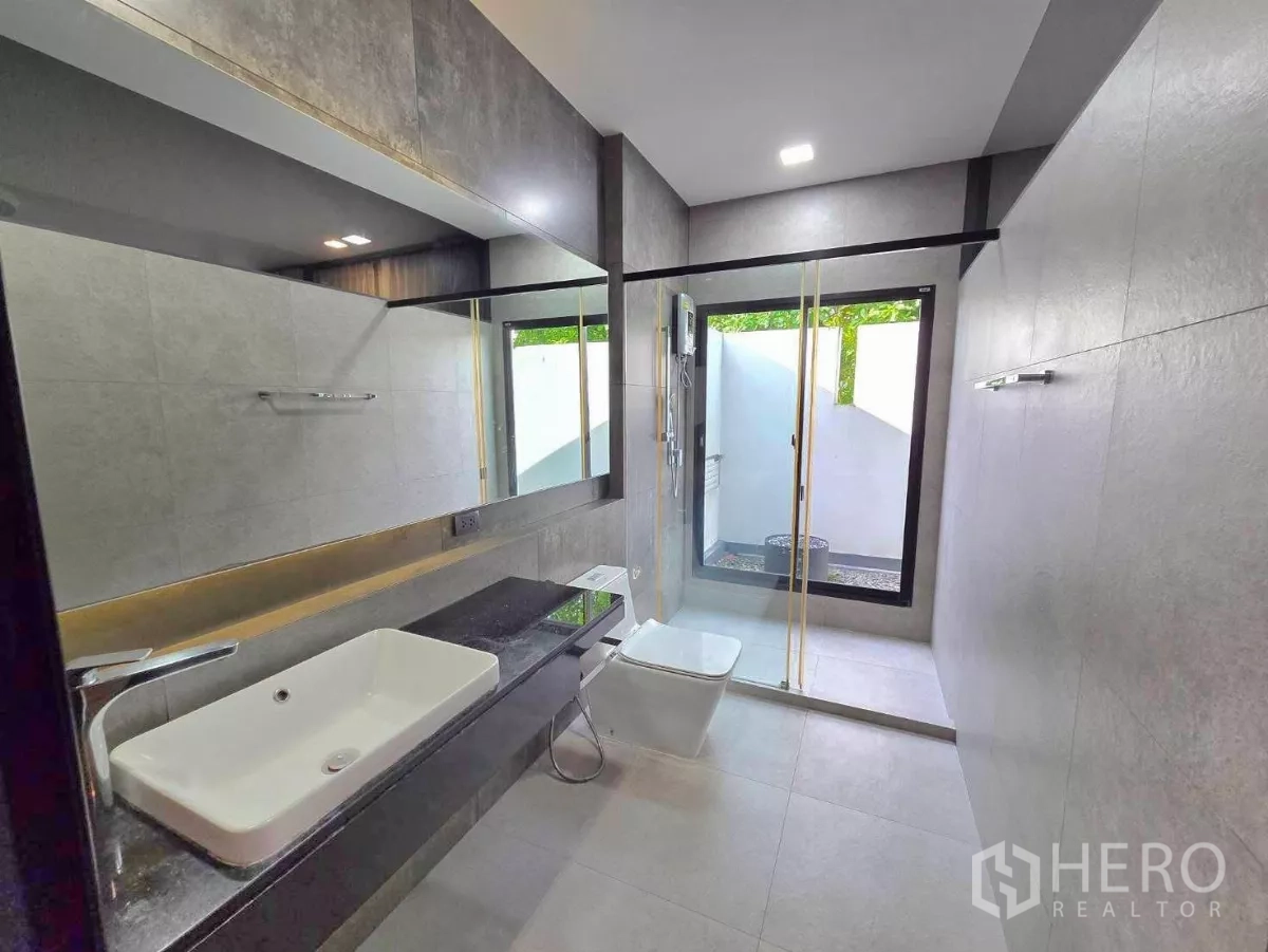 Detached House for rent in Bang Phli, Samut Prakan - Modern bathroom with long vanity, large mirror and a walk-in glass shower to a private courtyard.