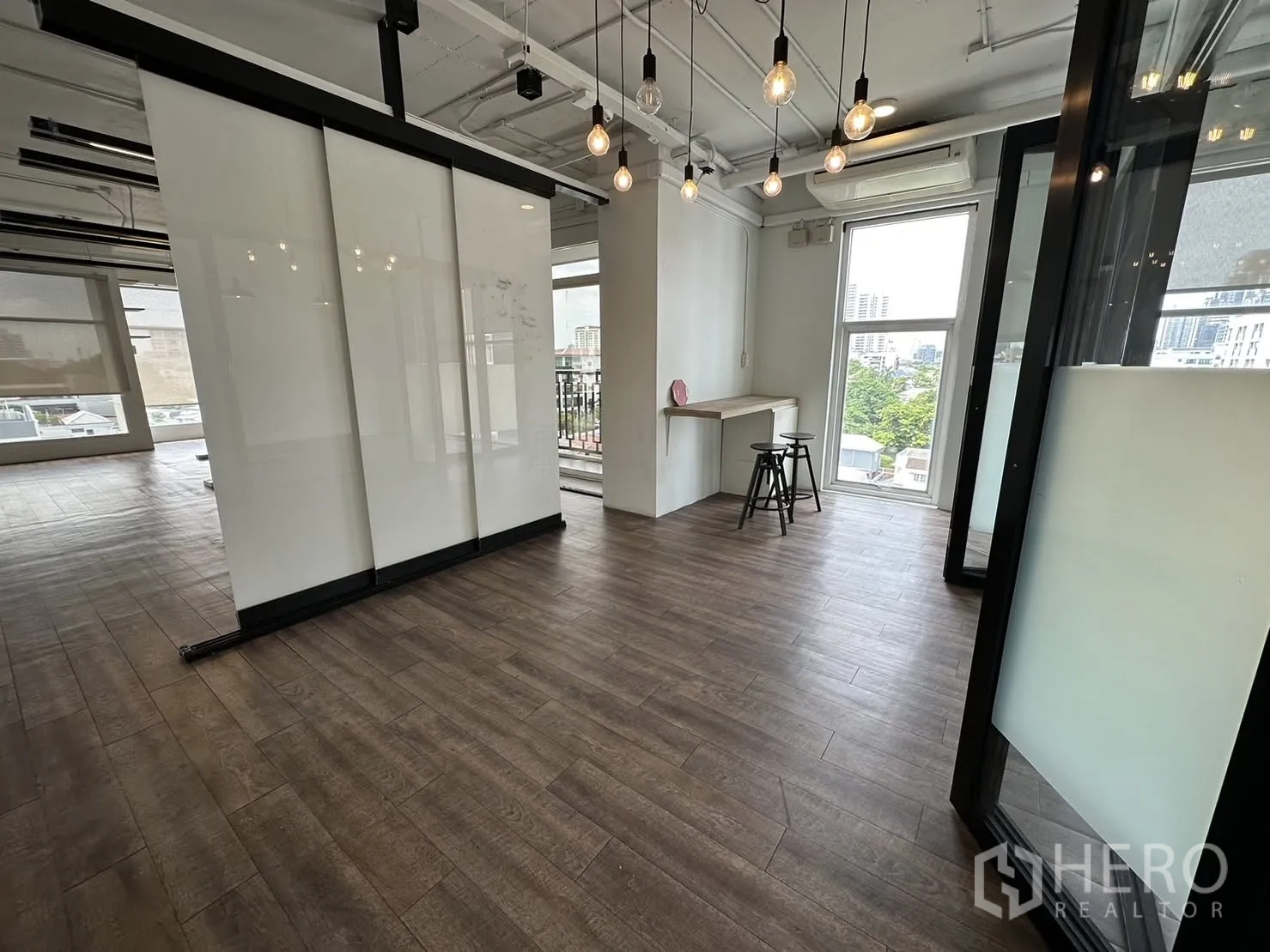 ออฟฟิศ for rent in Watthana, Bangkok - โถงทางเข้ามีโคมไฟหลอดเอดิสัน แผงกระจกสไลด์ฟรอสต์ และเคาน์เตอร์พร้อมสตูลข้างหน้าต่าง