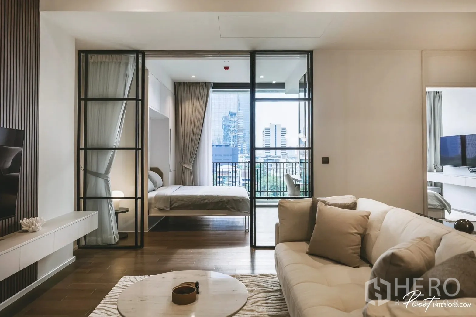 Condominium for rent in Pathum Wan, Bangkok - Living room facing a bedroom and balcony through full-height glass doors.