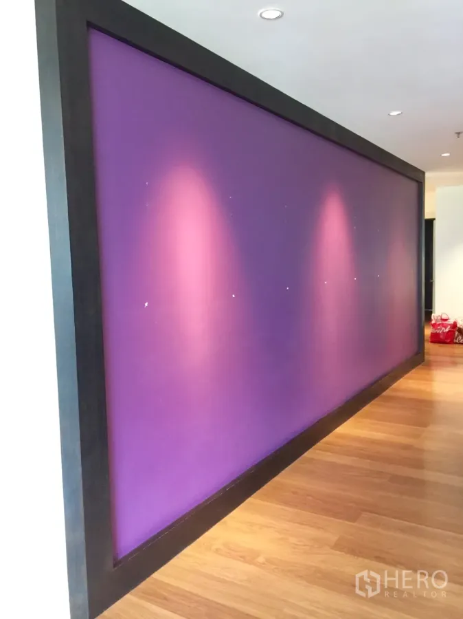 Condominium for rent in Watthana, Bangkok - Bangkok condo corridor with a purple feature wall, recessed ceiling lights and warm wood flooring.