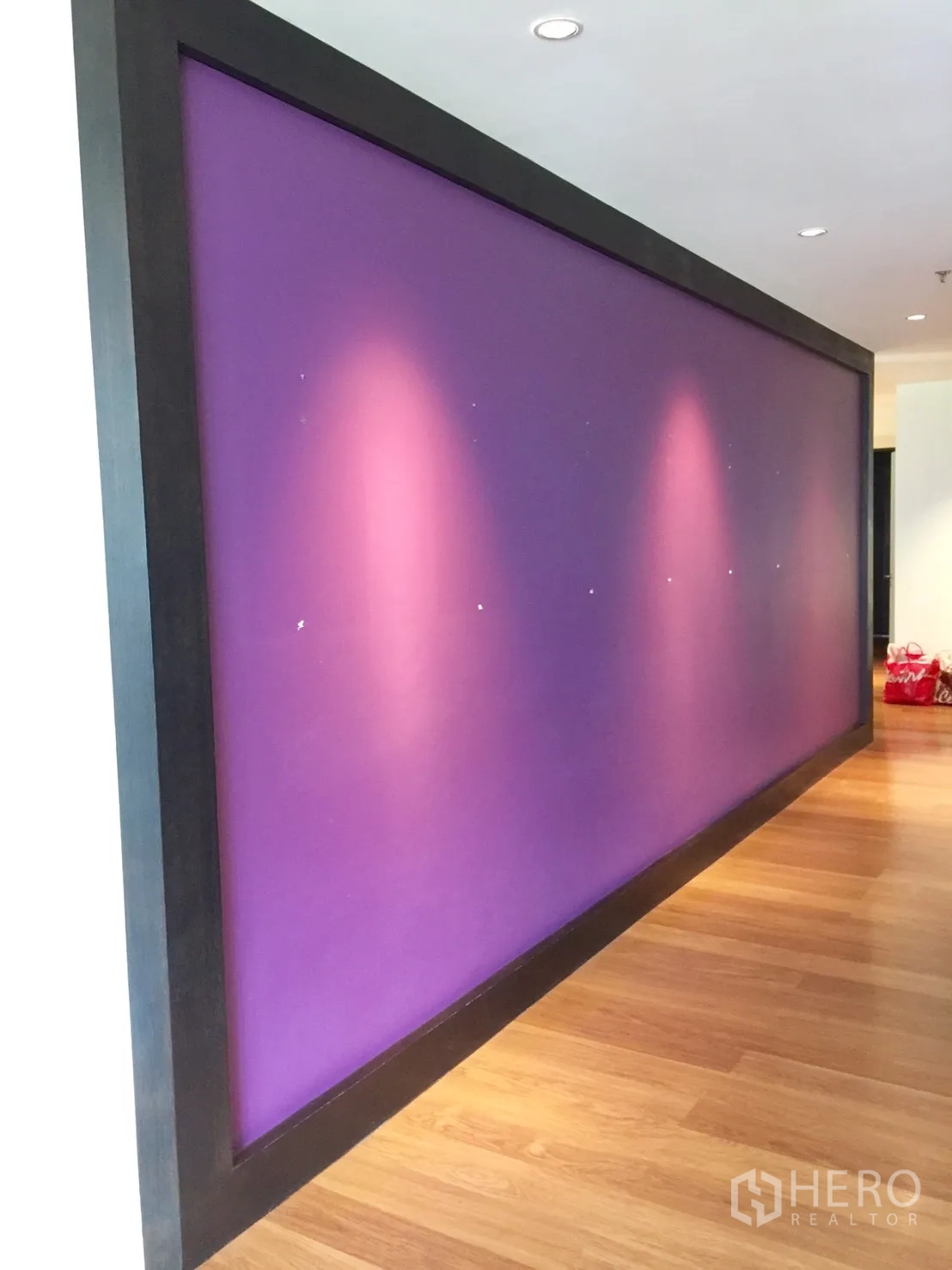 Condominium for rent in Watthana, Bangkok - Bangkok condo corridor with a purple feature wall, recessed ceiling lights and warm wood flooring.