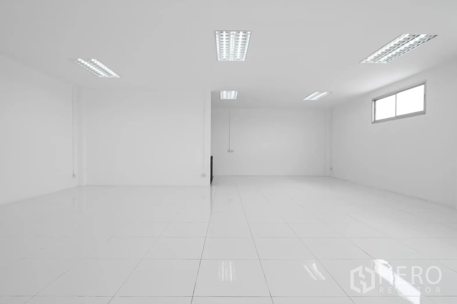 Factory for rent in Pathum Thani - Minimalist white office room with tiled floor and a small window.