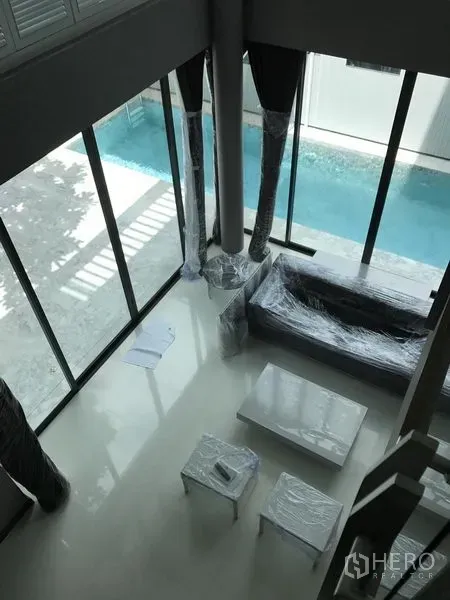 บ้าน ให้เช่าในBang Kapi, Bangkok - ห้องนั่งเล่นเพดานสูง ผนังกระจกเต็มบาน มองเห็นสระว่ายน้ำส่วนตัว