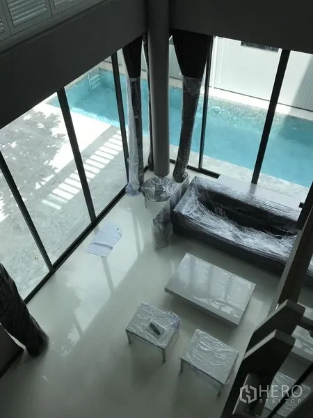 บ้าน ให้เช่าในBang Kapi, Bangkok - ห้องนั่งเล่นเพดานสูง ผนังกระจกเต็มบาน มองเห็นสระว่ายน้ำส่วนตัว