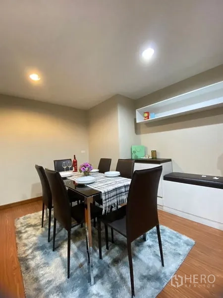 Condominium for rent - Dining area with six-seat table on a rug and floating wall shelves.
