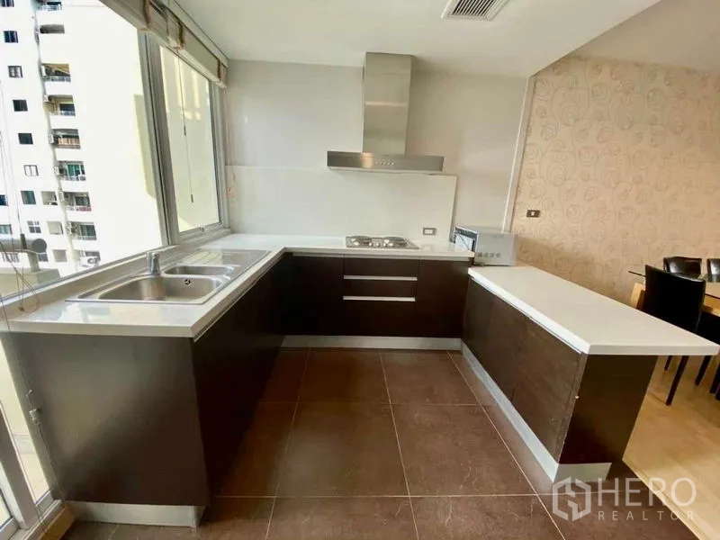 คอนโด ให้เช่าหรือขายในWatthana, Bangkok - ครัวรูปตัว U สว่าง เคาน์เตอร์สีขาวและเครื่องดูดควันสเตนเลส