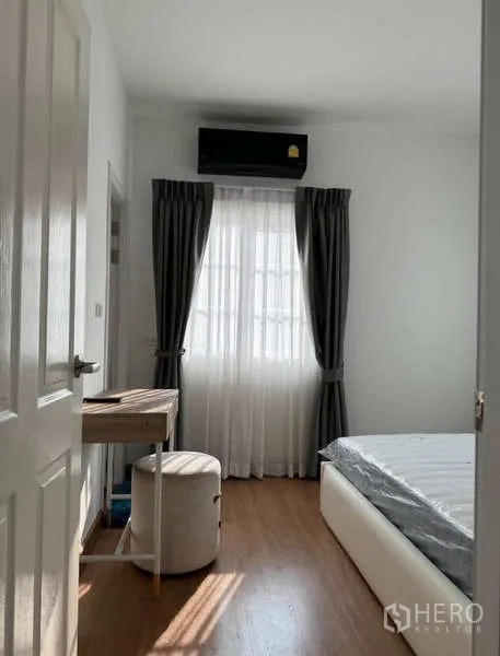 Detached House for rent in Bueng Kum, Bangkok - Secondary bedroom with bed, window drapes and wall-mounted air conditioner.