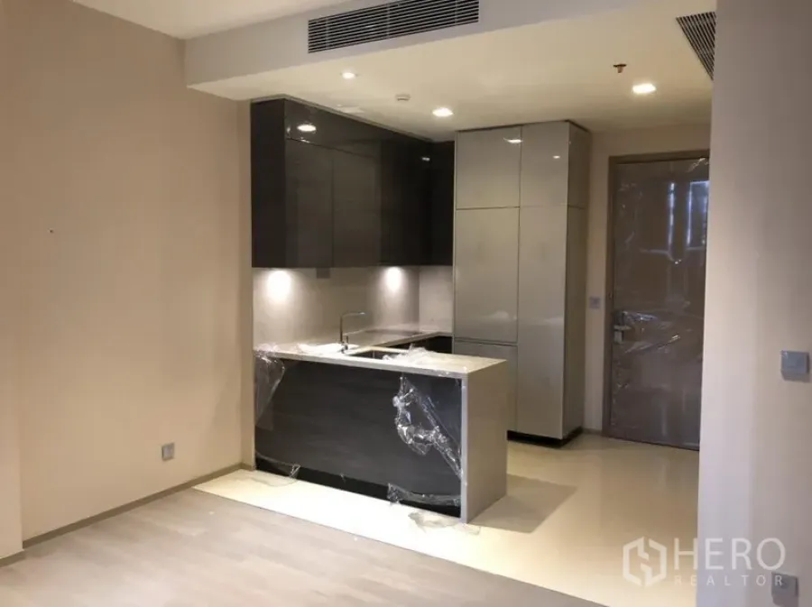 Condominium for rent or sale in Watthana, Bangkok - Modern kitchenette with island, glossy cabinets and recessed lighting in an open-plan living area
