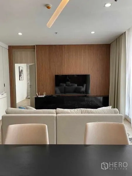 Condominium for rent in Pathum Wan, Bangkok - Living room facing TV console on wood slat feature wall with cream sofa.