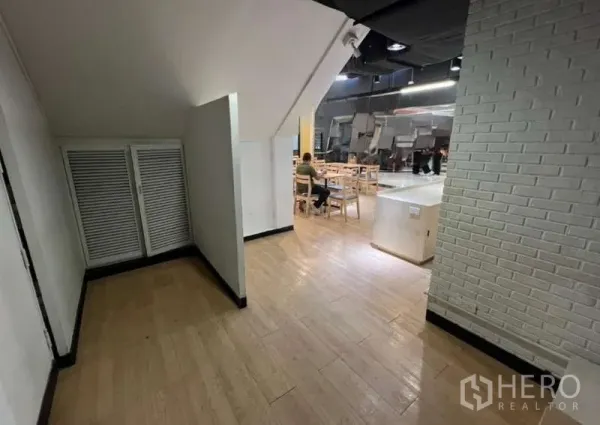 零售空间 出租在Watthana, Bangkok - 走廊带楼梯下储物区，连接到木质地板的座位区的店铺空间。