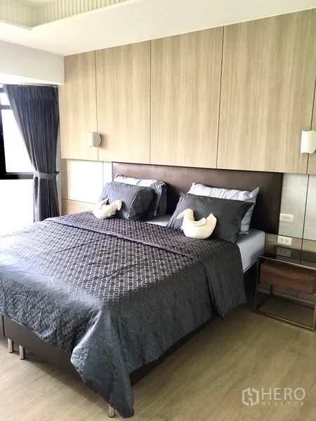 公寓 出租在Watthana, Bangkok - 主卧配大床，木质墙板、床头灯与落地窗帘