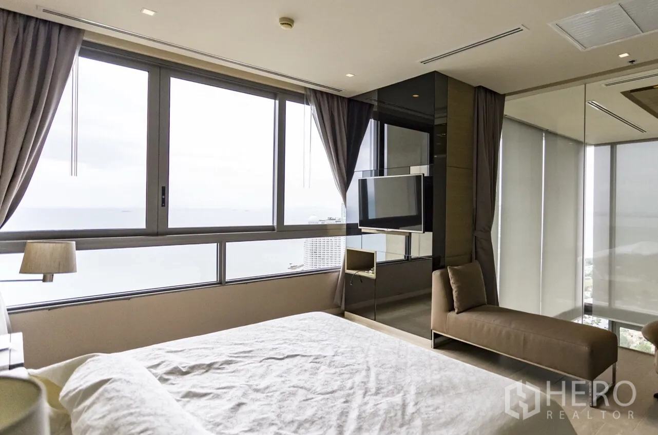 Condominium for rent in Bang Lamung, Chon Buri - Master bedroom with panoramic sea-view windows and wall-mounted TV.