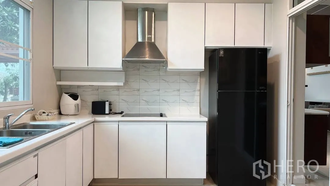 Detached House for rent in Lat Krabang, Bangkok - Modern kitchen with stovetop, hood and tall black fridge.