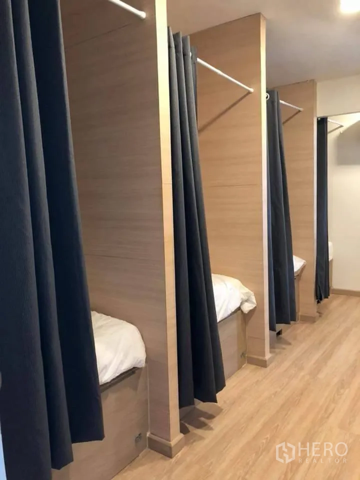 独栋房屋 for rent in Watthana, Bangkok - 一排带帘的内置睡眠舱，走道铺木地板。