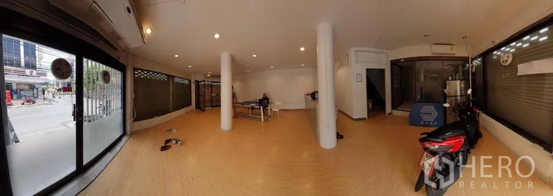 Shophouse for rent in Sathon, Bangkok - Spacious ground-floor retail area with glass frontage, support columns and wood-look flooring.