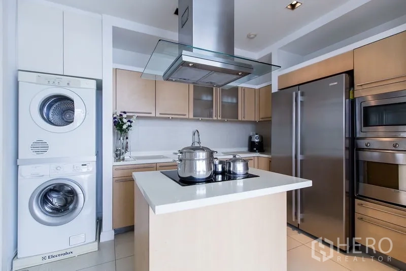 Condominium for rent in Pathum Wan, Bangkok - Kitchen with island, stacked washer and dryer, side-by-side fridge, and built-in ovens.